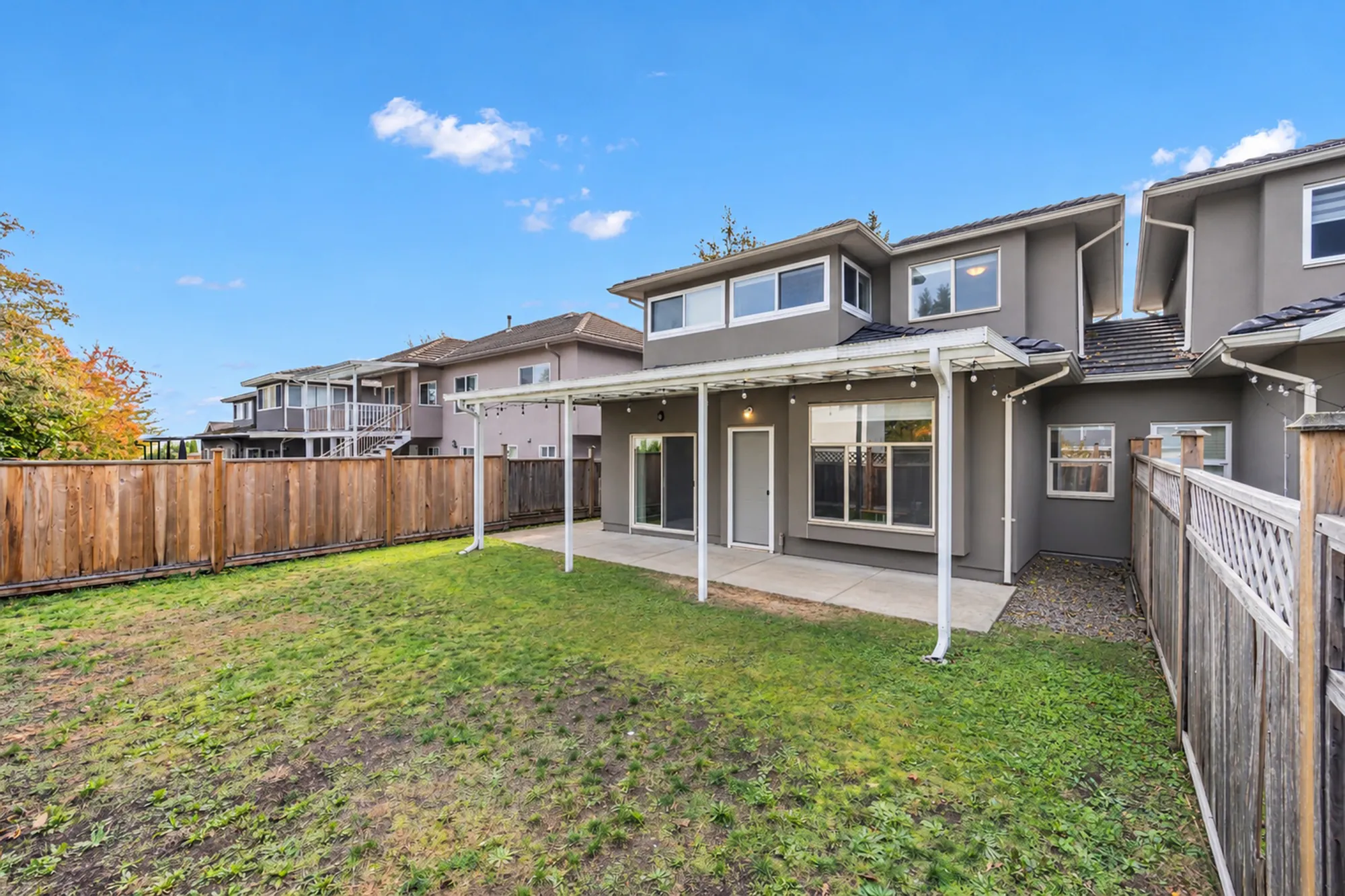 The back yard toward the house: the lawn, the covered patio and the side fences