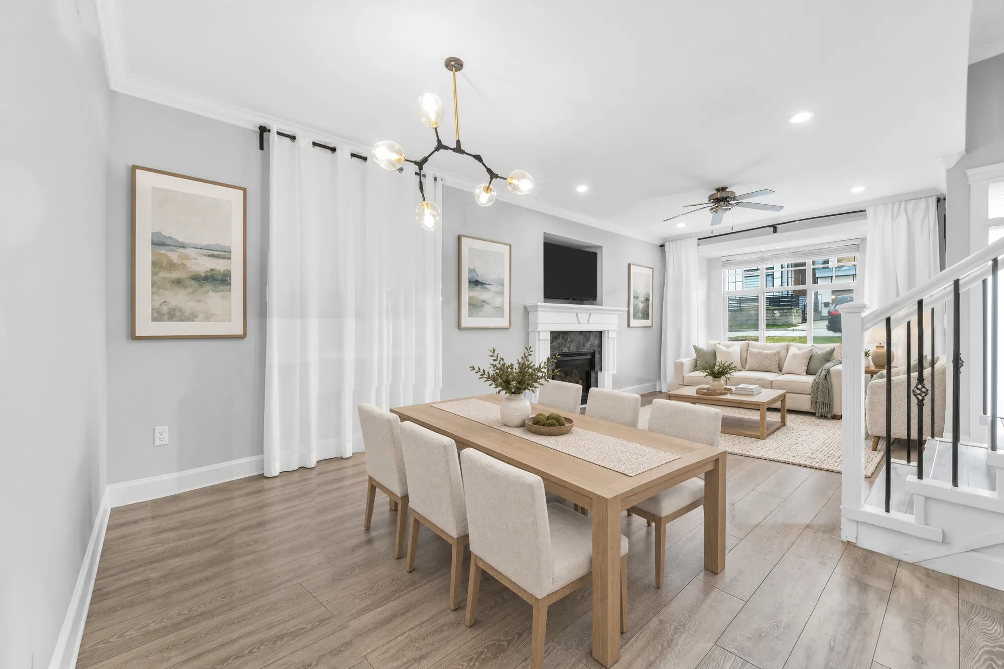 The dining room toward the living room, virtually staged: the table and chairs, the fireplace and a sofa beyond