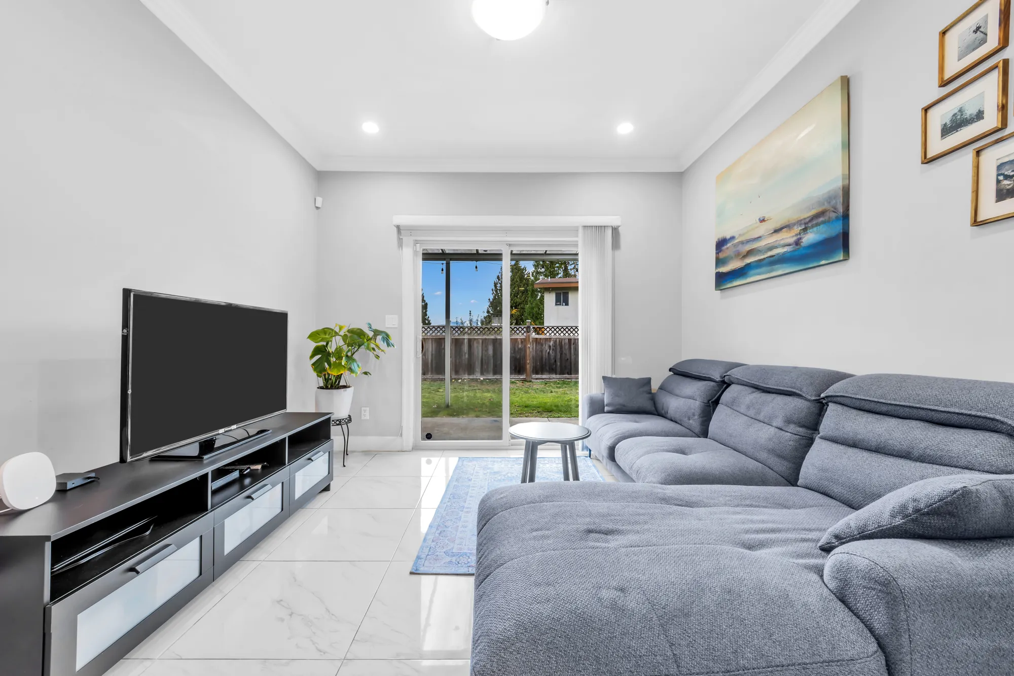 The family room toward the sliding door: the sectional, a round side table, framed prints