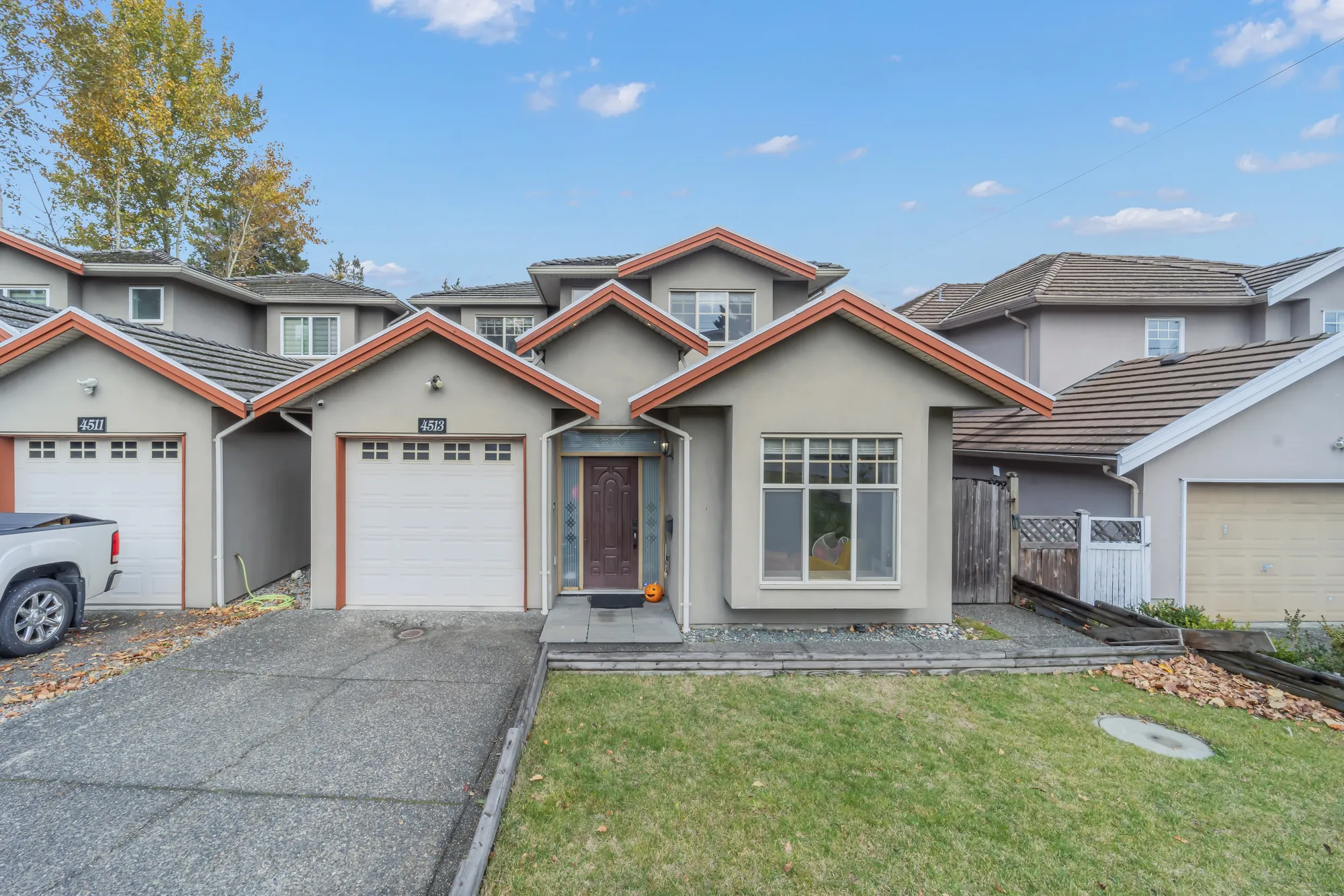 The front of 4513 Ellerton Court: grey stucco under red-orange trim, a single garage door with the number 4513 above it, a wood front door, a bay window, a lawn beside the drive