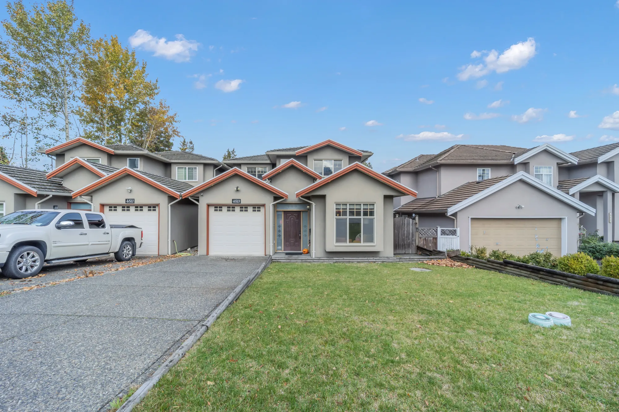 The front across the lawn: the garage, the front door and the bay window, a pickup on the next drive