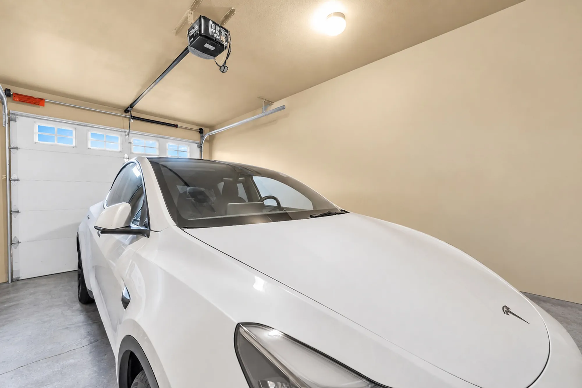 The single garage, a car parked inside, white walls, an automatic opener