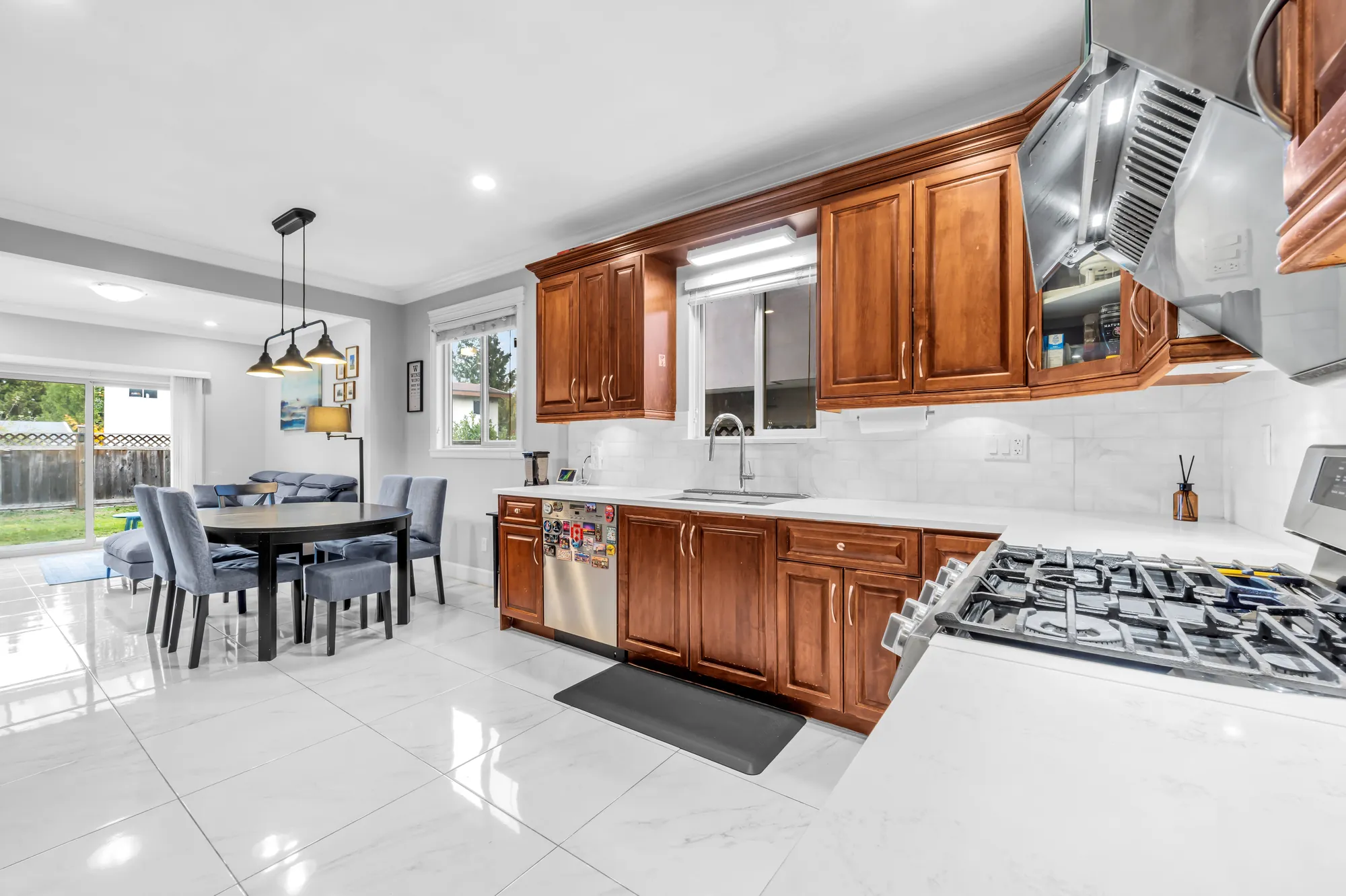 The kitchen from the counter end: a gas cooktop set in the counter, the sink under a window, the breakfast area beyond