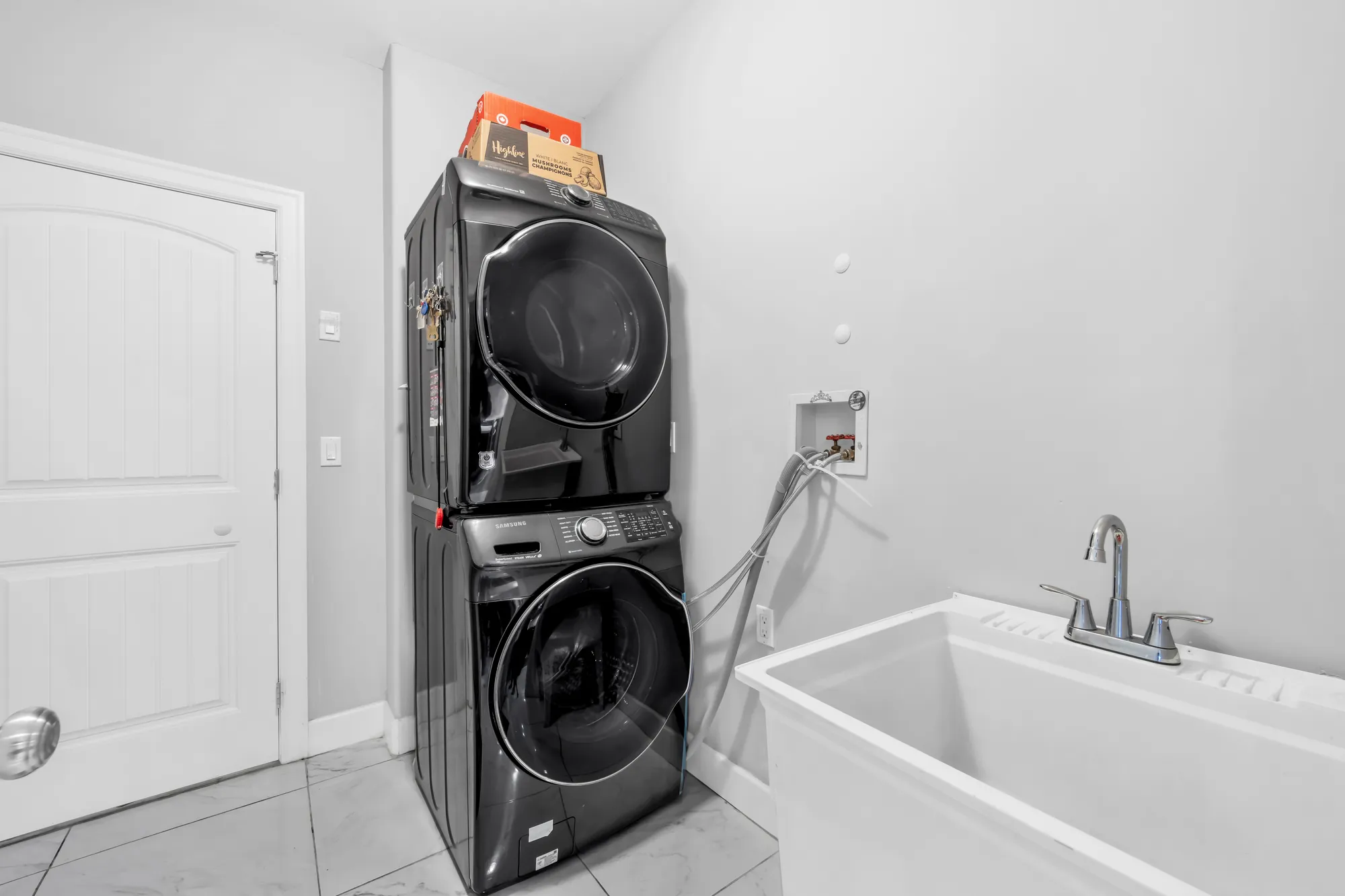 The laundry room: a stacked washer and dryer, a laundry sink, a door