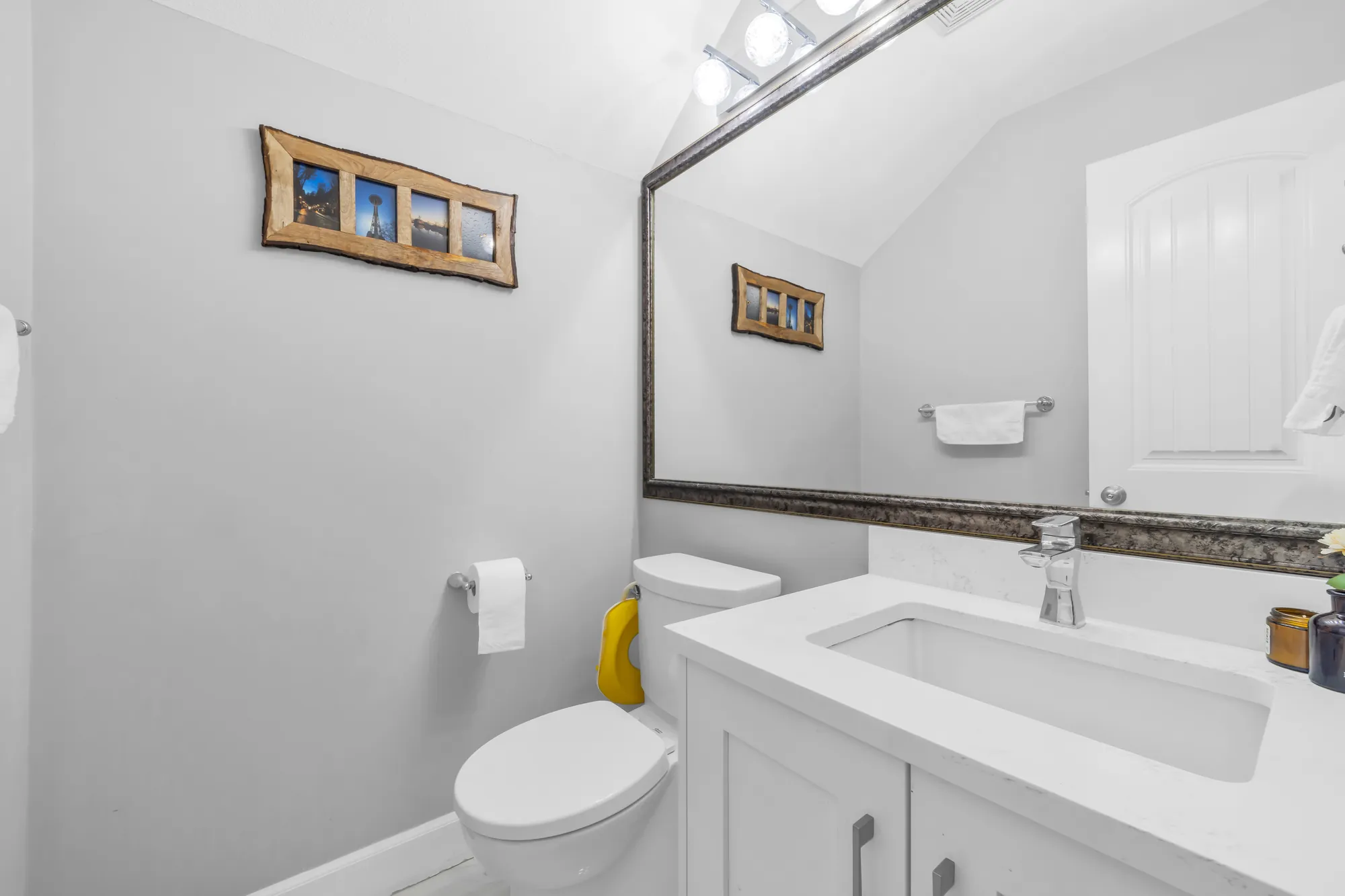 The powder room: a white vanity with a stone top, a toilet, a wide mirror
