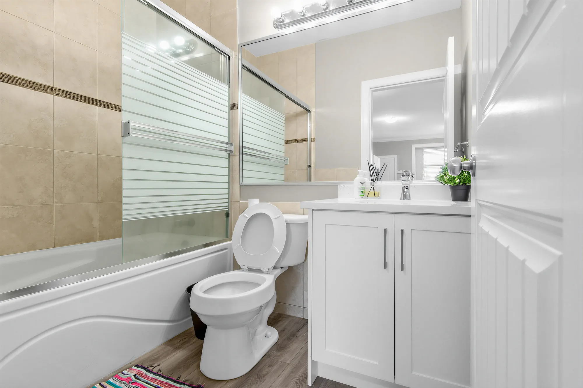 The guest suite's bathroom: a tub with a sliding glass screen, a white vanity, a toilet