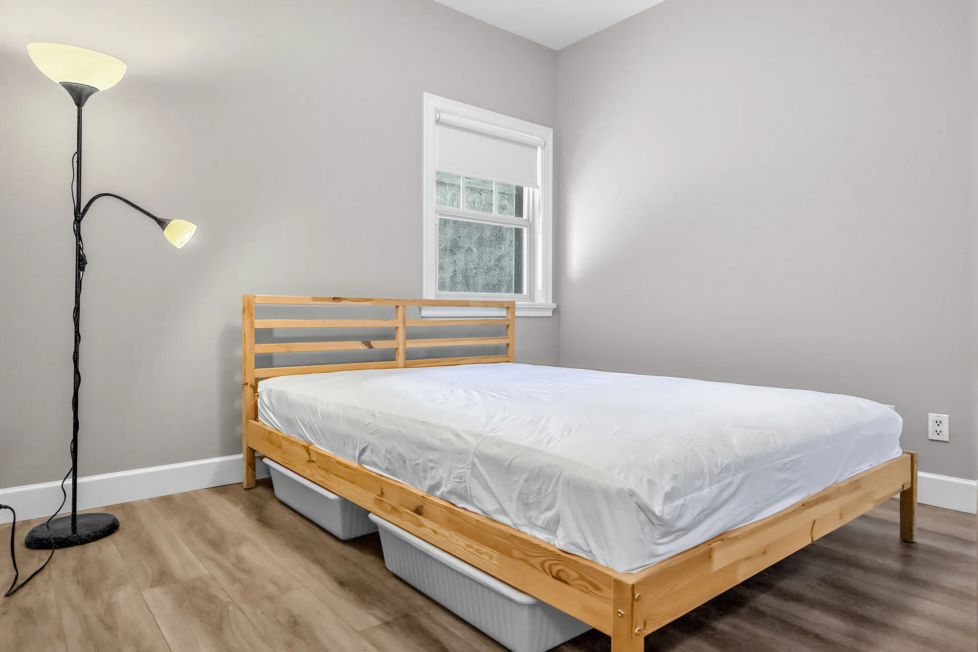 The other bedroom in the guest suite: a pine bed, a floor lamp, a window