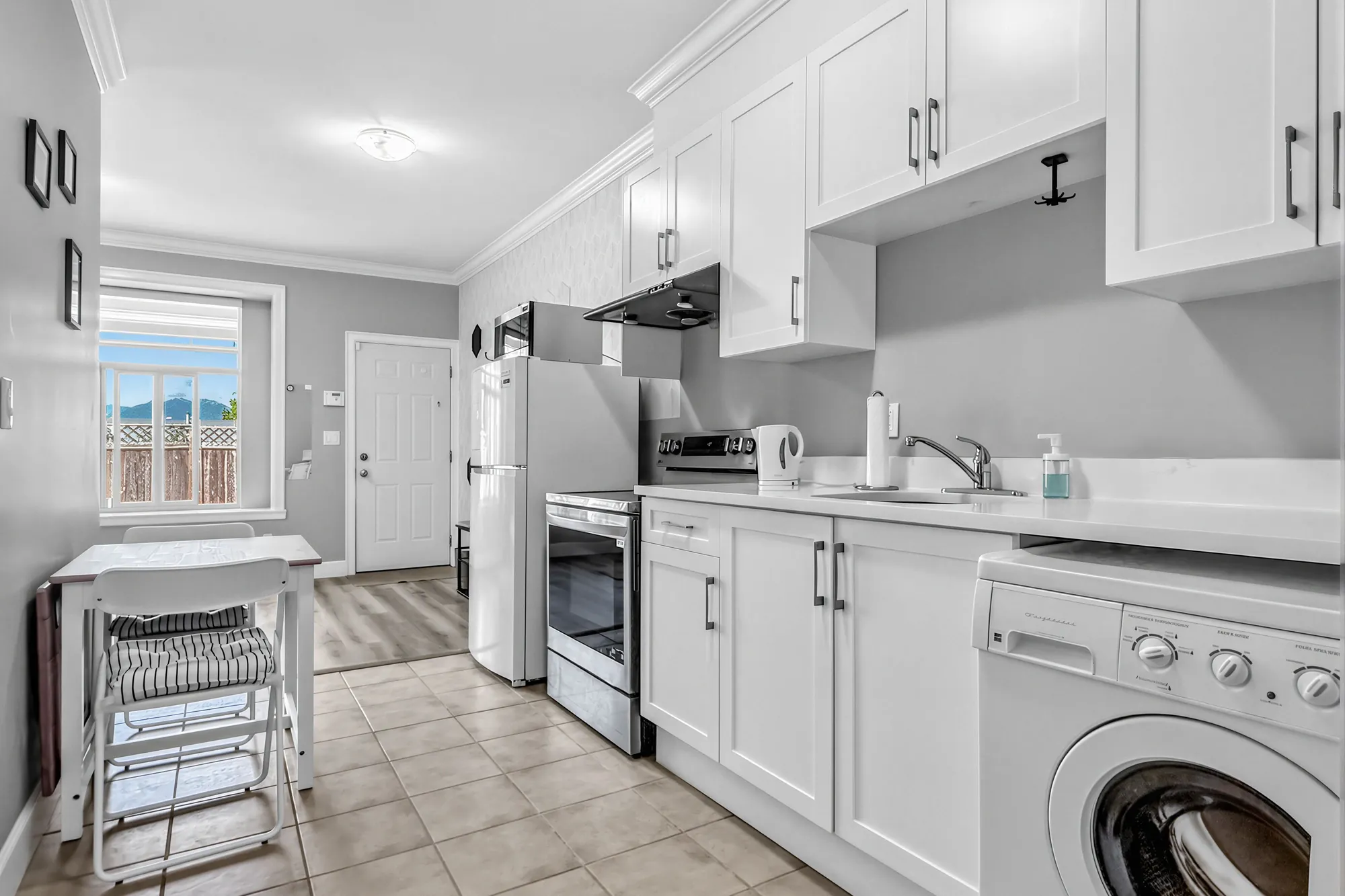 The guest suite's kitchen: white cabinets, a stainless range, a front-loading washer, a window at the end