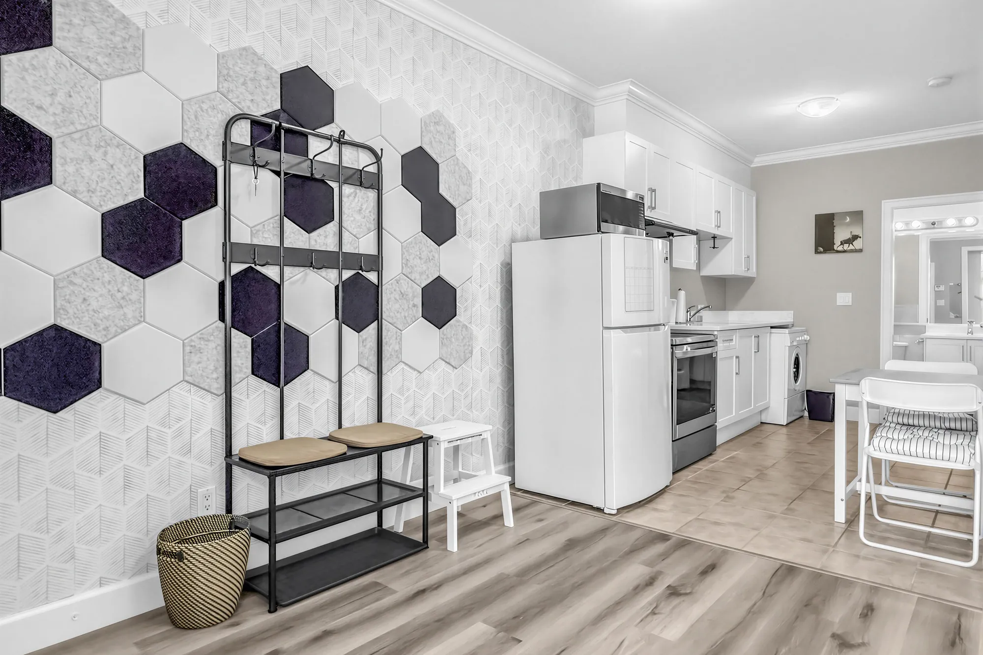 The guest suite's entry and kitchen: a wall of hexagon panels, a coat rack and bench, a white fridge and range